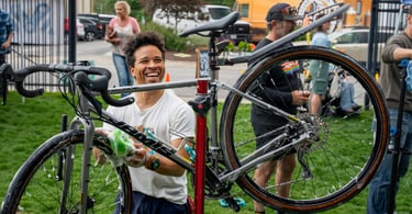 Smiling young man washing a bike with a sponge