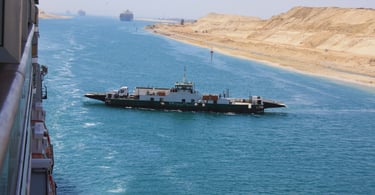 foto do navio navegando pelo canal de suez a frente de um barco local