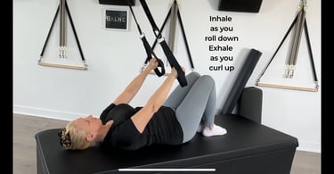 a woman pressing down on a suspension trainer with her arms
