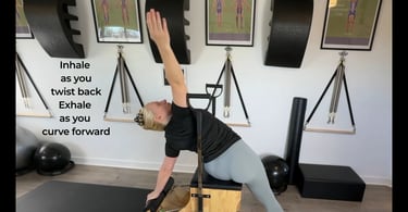 a woman stretching to the side with the Pilates Chair