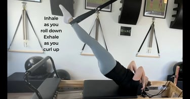 a woman working a bridging motion while on the reformer with a suspension trainer