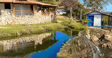 Queda d'água da Cachoeira do Comércio descendo por paredão de pedra em área de mata nativa