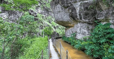 Passarela estreita passando sob uma imponente rocha suspensa no Cânion do Funil em Santo Antônio do 