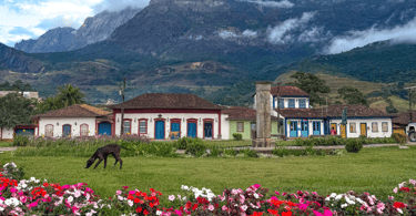 Praça Central de Catas Altas, com jardim, casas históricas e montanhas ao fundo, centro turistico