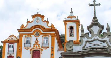 Igreja histórica em São João del-Rei com fachada branca e amarela, torre com sino e cruz