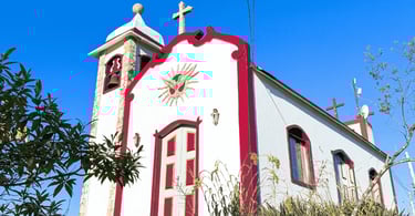 Capela do Senhor do Bonfim com cores brancas e vinho, céu azul sem nuvens em Ipoema