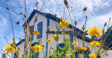 Capela histórica com flores amarelas em frente, em Betim, Minas Gerais, pertinho de BH