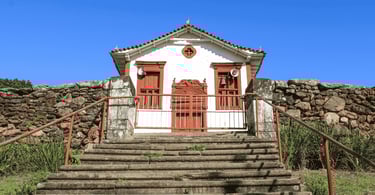 Igreja histórica em Itapanhoacanga MG com escadaria frontal, muro de pedra e céu azul ao fundo