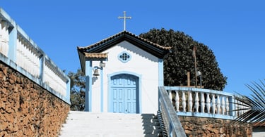 Capela com porta azul, escadaria branca e céu aberto em Ouro Branco, Minas Gerais
