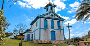 Capela em Três Barras, distrito do Serro, com fachada azul, cruz e céu claro em Minas Gerais