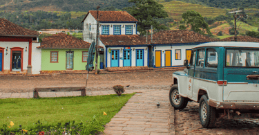 Ruas de pedras com um carro antigo e casas coloniais ao fundo em Catas Altas