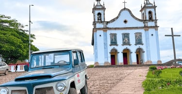 Igreja histórica com carro antigo, rua de pedra e jardim em Catas Altas, Minas Gerais
