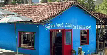 Fachada de casa colonial azul com porta e janelas vermelhas e telhado de barro. Lavras Novas, MG