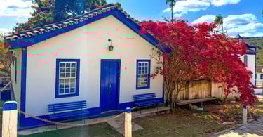 Casa em azul e branco, do periodo colonial, com uma árvore florida em frente, na Vila do Biribiri