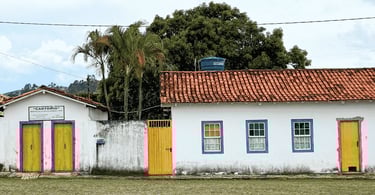 Casa do período colonial com cor branca, janelas azuis e portas amarelas, em Cachoeira do Campo