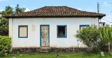 Casa antiga em Chapada, distrito de Ouro Preto, com fachada branca, detalhes azuis e telhado colonia
