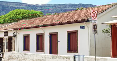 Casa do período colonial em cor branca e detalhes em vinho, com a Serra de São José em Tiradentes