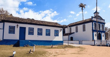 Estrada de terra, casa histórica e igreja historica, com cores branca e azul, na Vila do Biribiri