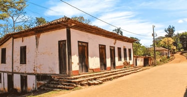 Casa histórica em Milho Verde com paredes brancas, janelas de madeira e rua de pedra
