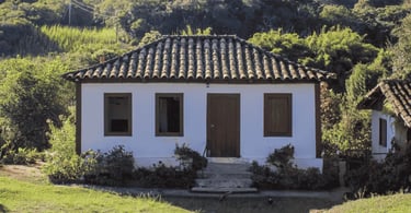 Casa histórica de arquitetura simples em Casa Grande, Minas Gerais, cercada por vegetação e área rur