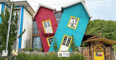 Casa torta, colorida em Bichinho, com fachadas azul e vermelha, janelas amarelas e visual criativo