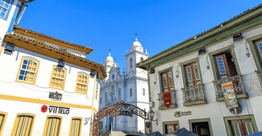 Casarões coloniais em Diamantina emolduram a igreja ao fundo, com o arco da Vesperata sob céu azul