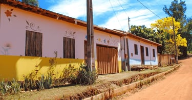 Casas simples, coloridas e decoradas com flores ao longo de uma tranquila rua de terra, Milho Verde