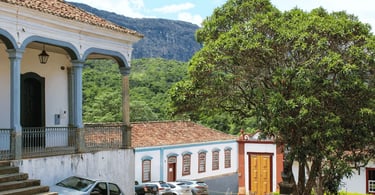 Casas do periodo colonial e uma árvore a frente, com montanha ao fundo em tiradentes MG