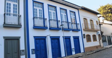 Casarões históricos com portas azuis, sacadas de ferro e rua de pedra em Sabará MG