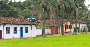 Casas de cores branca e amarela, com arvores a frente no distrito de Brumal em Minas Gerais