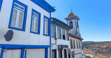 Fachadas de casarões com detalhes em azul e torre de igreja ao fundo em Diamantina