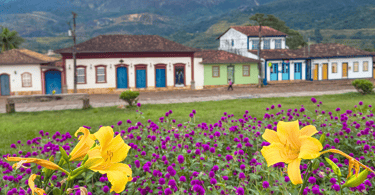 Flores e plantação na praça central de Catas Altas, com casas historicas ao fundo