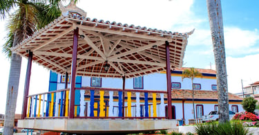 Coreto colorido na praça central de Datas, Minas Gerais, com igreja ao fundo