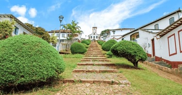 Escadaria histórica de pedra no Serro MG cercada por casarões coloniais e igreja ao fundo