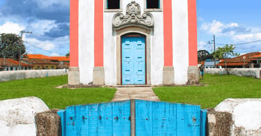 Igreja em Lavras Novas com porta azul, fachada colonial e gramado no entorno