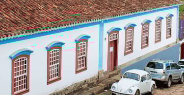 Casarão colonial em Tiradentes MG com fachada branca e azul, janelas em sequência, telhado antigo