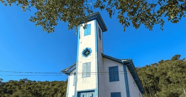 Igreja de Santo Antônio em Tapera, Minas Gerais, com fachada azul, árvores e céu aberto