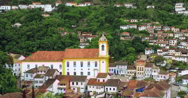 Vista panorâmica de Ouro Preto MG com igreja histórica, casario colonial e morros verdes ao fundo
