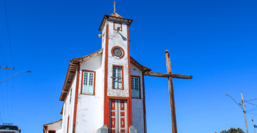 Uma igreja histórica e barroca, com uma cruz, em Alvorada de Minas, destino turistico mineiro