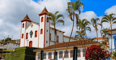 Igreja histórica, com casa do periodo colonial e coqueiros em Serro Minas Gerais