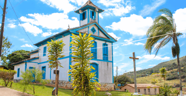 Igreja, árvores, cruz e um cachorro, no centro turistico de Três Barras, distrito de Serro MG