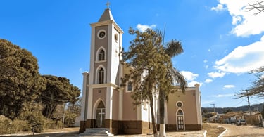 Igreja Matriz de Conselheiro Mata em Diamantina MG com torre alta, palmeiras e céu azul