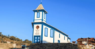 Igreja Matriz de Córregos MG com fachada colonial azul e branca, muro de pedra e céu aberto