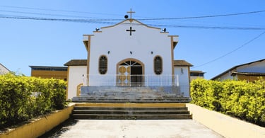Igreja de São Pedro de cores brancas e amarelas, com escadria e jardim em Cristiano Otoni