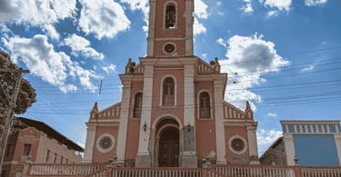 Igreja Matriz de fachada rosa e branca sob céu azul em Dores de Campos, Minas Gerais