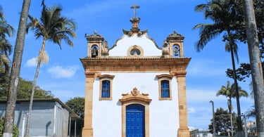 Igreja de Santo Antônio em Mateus Leme, com fachada colonial, porta azul e palmeiras ao redor