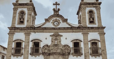 Igreja Matriz de Prados, em Minas Gerais, com fachada colonial, torres e relógio central