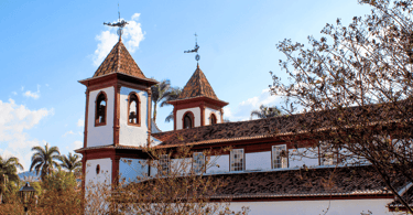 Igreja Matriz de Sabará, com árvores a frente e um céu azul aberto