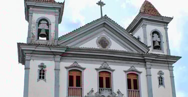 Igreja Matriz de Santa Bárbara, MG, com fachada branca, torres sineiras e janelas centrais