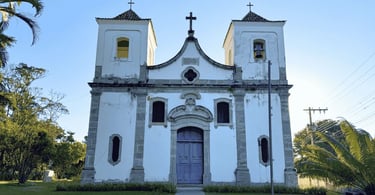 Igreja Matriz de Acuruí MG com fachada branca e torres coloniais ao céu aberto